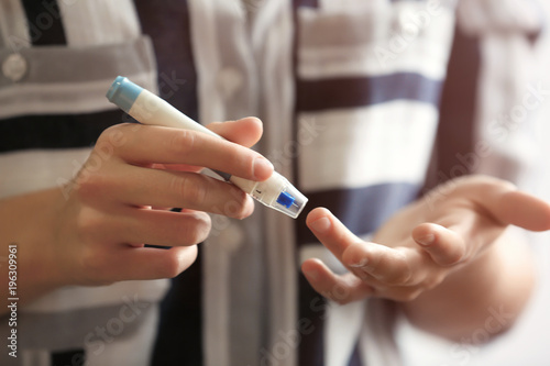 Diabetic woman taking blood sample with lancet pen, closeup