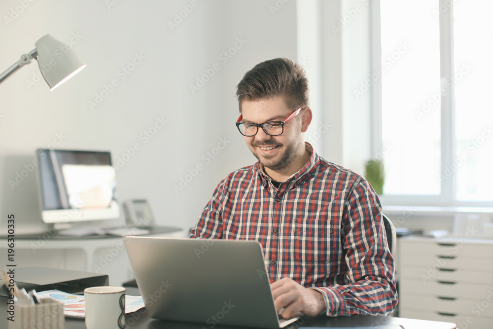 Young man with laptop working in office Young man with laptop working in office