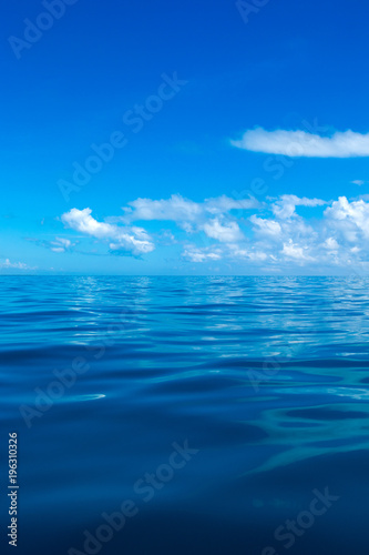 clouds on blue sky over calm sea with sunlight reflection
