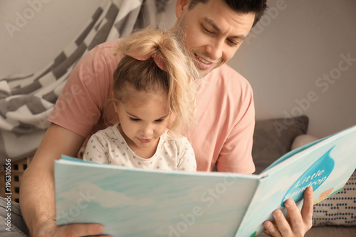 Father with little daughter reading bedtime story near hovel at home