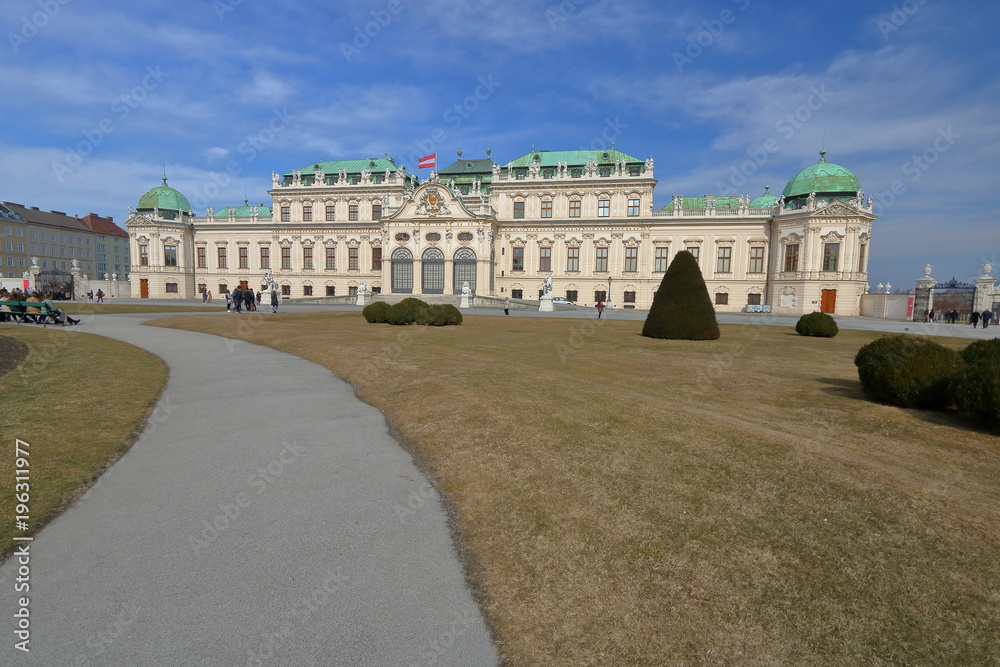 Beautiful panoramic view at palace garden in early spring and building of wonderful palace, few tourists walk, blue sky with picturesque clouds