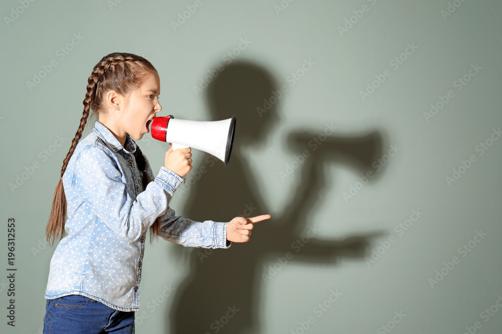 Angry little girl shouting into megaphone on color background Angry little girl shouting into megaphone on color background