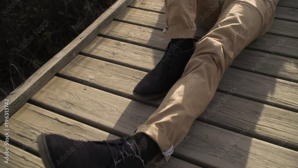 Dreaming adult man relaxing from daily rush lying on wooden walkway in field with laptop near. Dreaming adult man relaxing from daily rush lying on wooden walkway in field with laptop near.