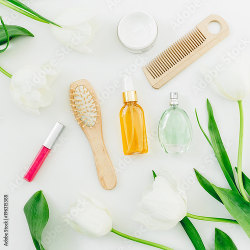Cosmetics, perfume, combs and tulips flowers on white background. Beauty composition. Flat lay, top view