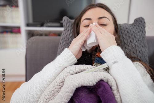 Young ill woman, blowing nose, lying at home