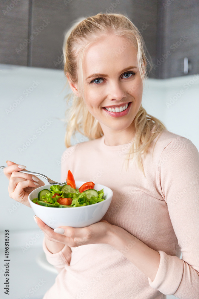 beautiful blonde girl holding bowl with fresh vegetable salad and smiling at camera beautiful blonde girl holding bowl with fresh vegetable salad and smiling at camera