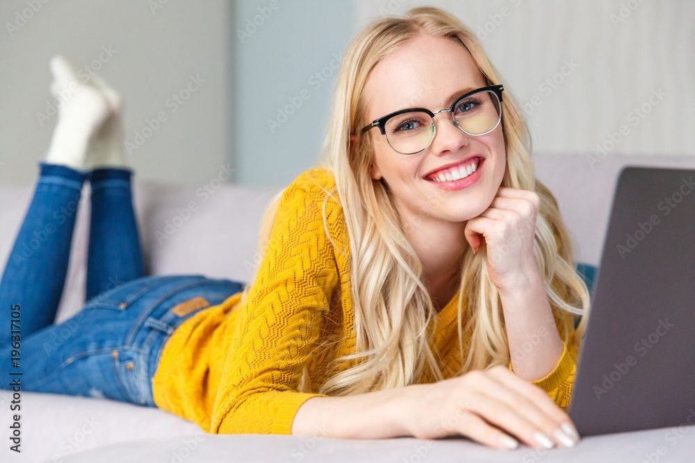beautiful blonde girl in eyeglasses using laptop and smiling at camera beautiful blonde girl in eyeglasses using laptop and smiling at camera