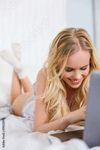 beautiful happy blonde girl using laptop on bed