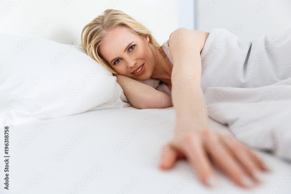 selective focus of beautiful young woman smiling at camera while lying in bed selective focus of beautiful young woman smiling at camera while lying in bed