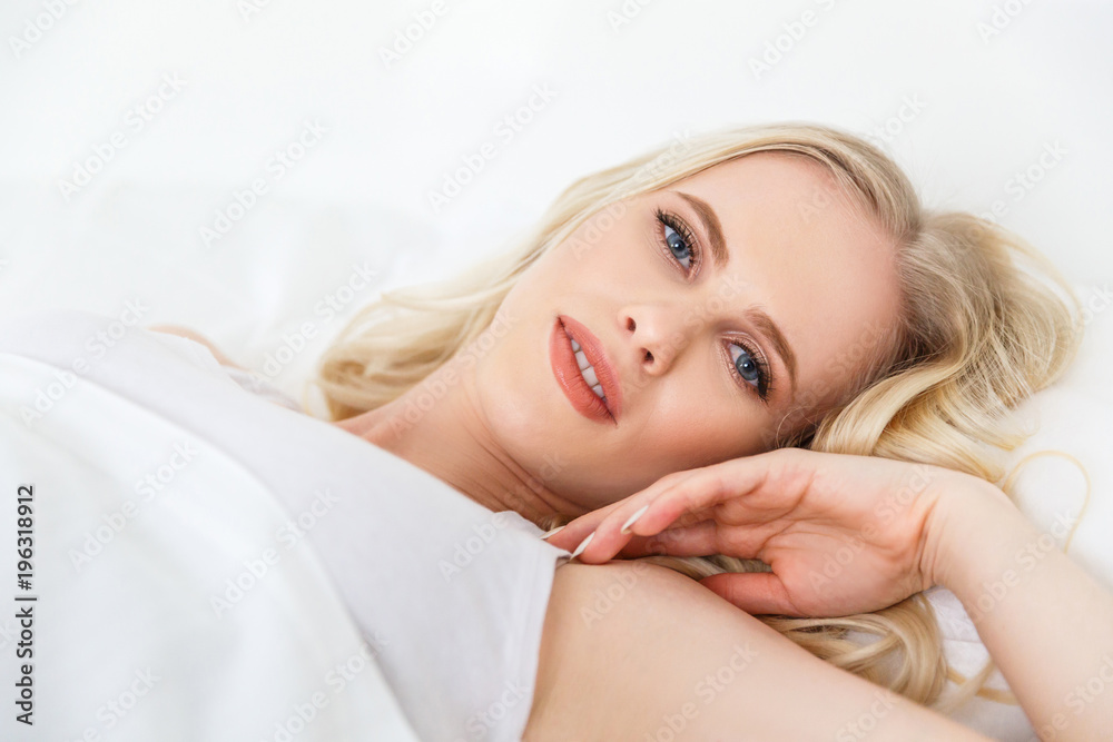 beautiful blonde girl lying in bed and looking at camera beautiful blonde girl lying in bed and looking at camera
