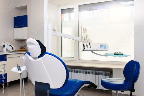 Interior of new modern dental clinic office room with chair in blue and white colors. Dentistry  stomatology  medicine medical equipment concept in teeth cabinet
