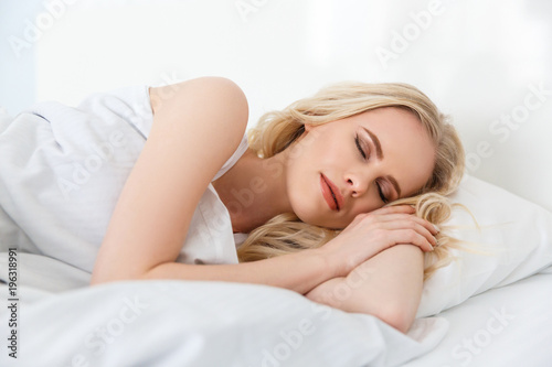 beautiful young blonde woman sleeping in bed
