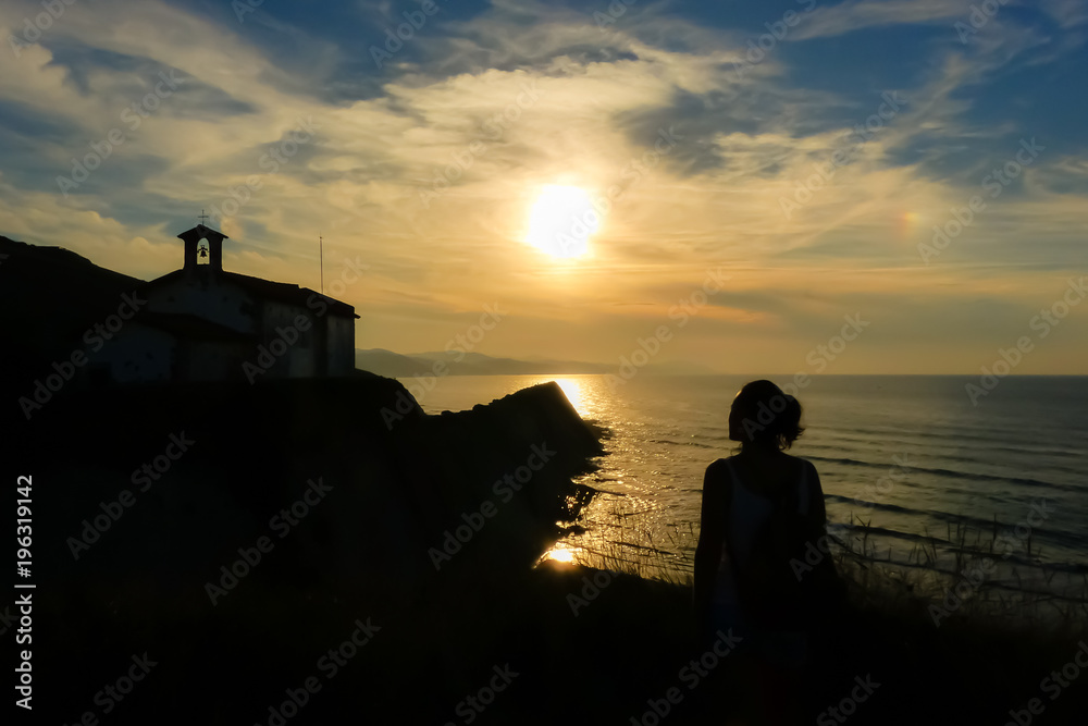 Sunset in the coast with church and woman silhouette
