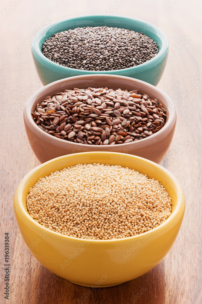 Chia, quinoa and flax seeds in a colorful bowls on a wooden background. Chia, quinoa and flax seeds in a colorful bowls on a wooden background.
