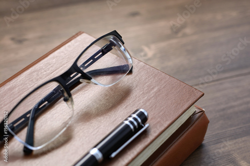 
Business accessories on desktop: notebook, diary, fountain pen, book, glasses. 