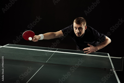 tennis player in uniform playing table tennis isolated on black