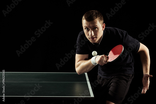 portrait of focused tennis player playing table tennis isolated on black