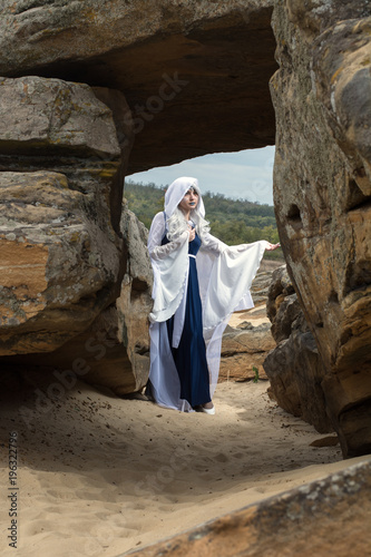 beautiful girl dressed in a princess elf. stands near the stone walls. Monument stone tomb photo