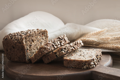 A loaf of fresh rustic rye bread on wooden board. Healphy food background. Close up. Copy space. Fitness wholegrain bread. photo