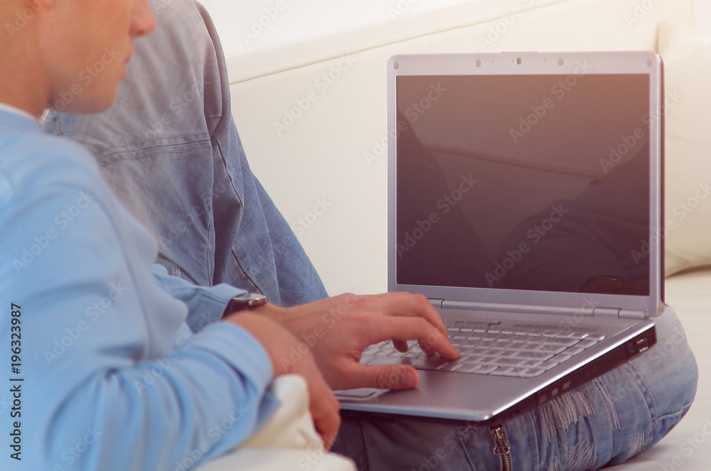 Young casual man working on laptop while lying on the couch. Young casual man working on laptop while lying on the couch.