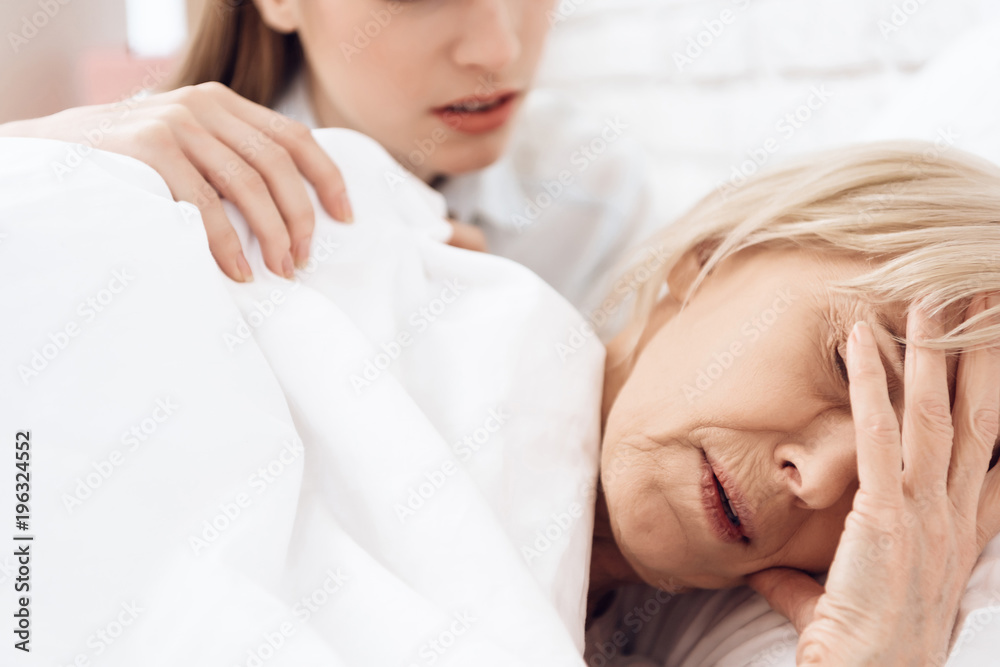 Girl is nursing elderly woman at home. Woman is feeling bad, girl is concerned. Girl is nursing elderly woman at home. Woman is feeling bad, girl is concerned.