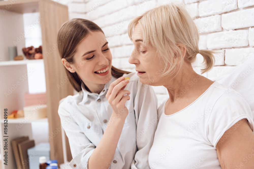 Girl is caring for elderly woman at home. Girl brings breakfast on tray. Girl is feeding woman. Girl is caring for elderly woman at home. Girl brings breakfast on tray. Girl is feeding woman.