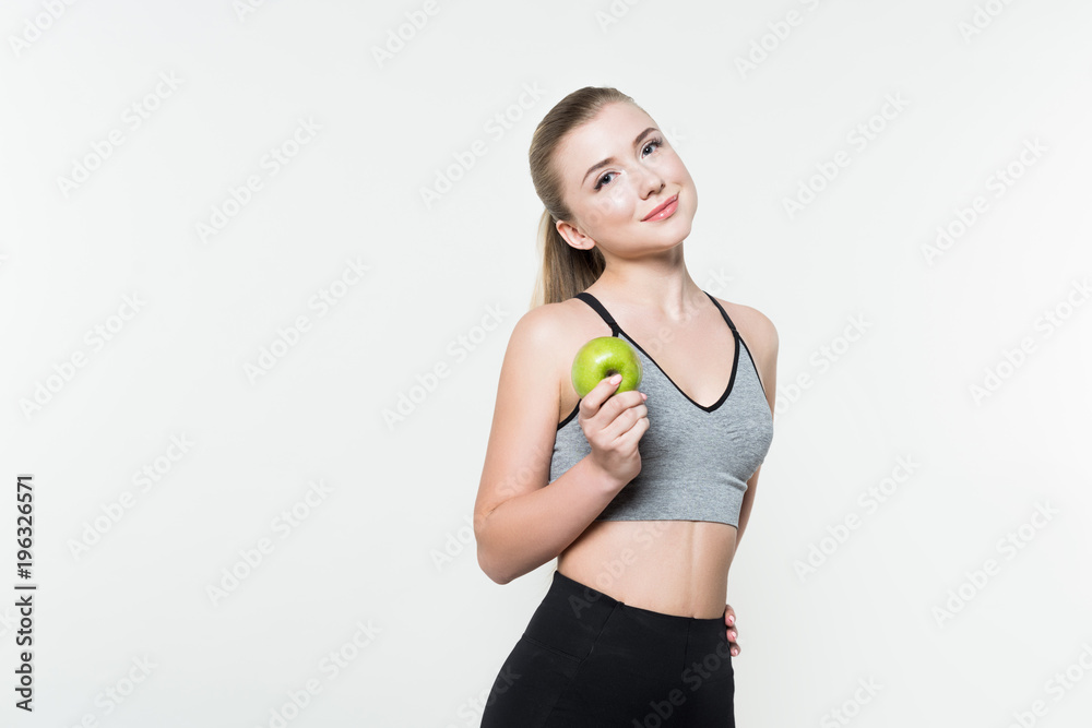 Young woman in sports top holding apple isolated on white Young woman in sports top holding apple isolated on white