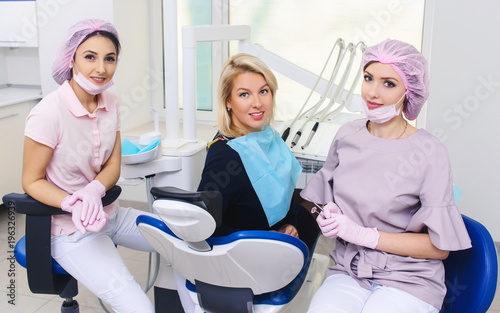 Portrait of young smiling dentists and female patient in dental stomatology clinic with white background