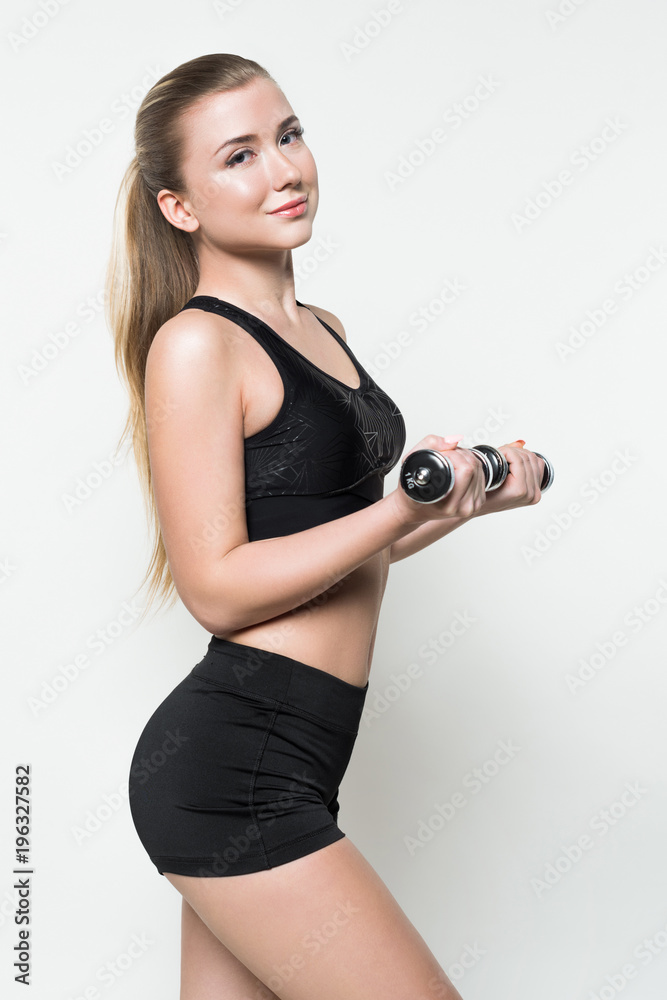 Fit girl training with dumbbells isolated on white Fit girl training with dumbbells isolated on white