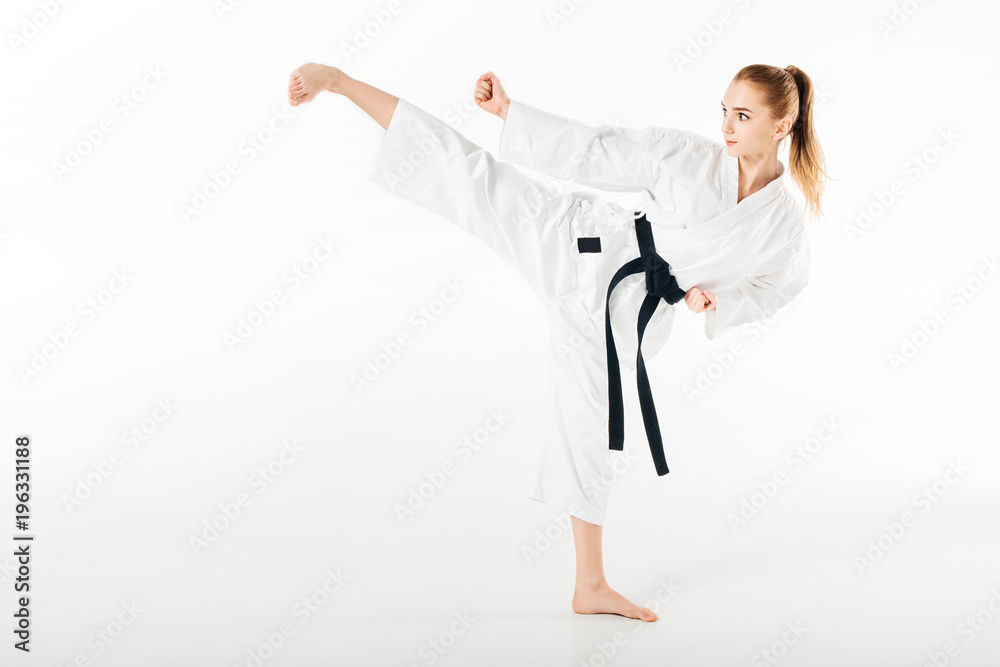 Female karate fighter training kick isolated on white