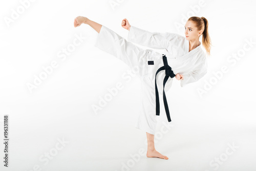 Female karate fighter training kick isolated on white