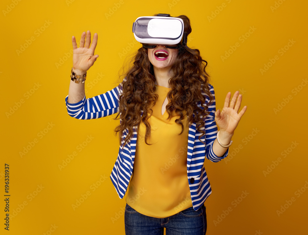 happy woman on yellow background using virtual reality headset