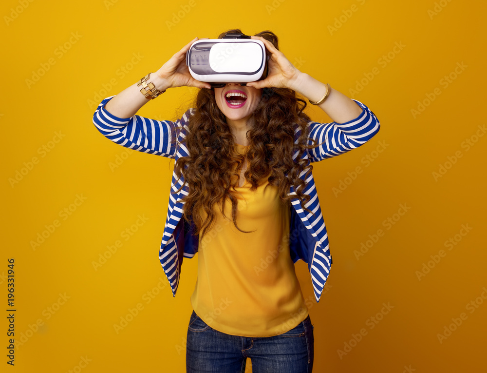 happy modern woman against yellow background using VR gear