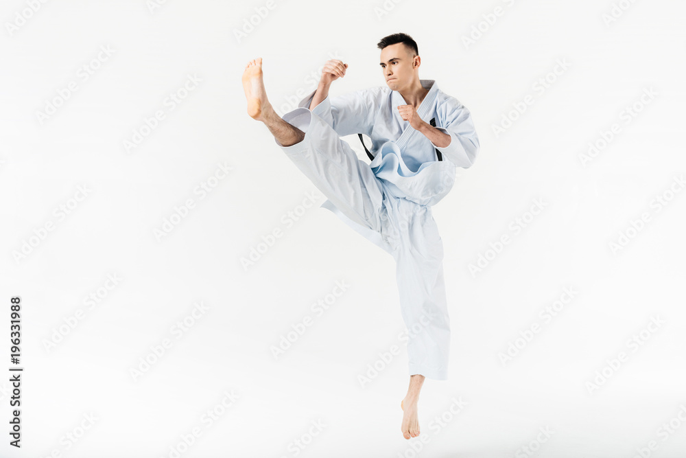 Male karate fighter performing kick isolated on white Male karate fighter performing kick isolated on white