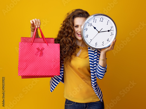 woman against yellow background with clock and shopping bags