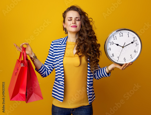 relaxed trendy woman showing clock and red shopping bags