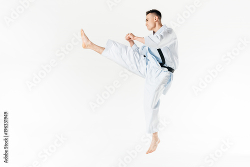 Side view of male karate fighter training isolated on white