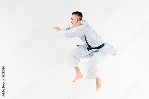 side view of male karate fighter jumping isolated on white