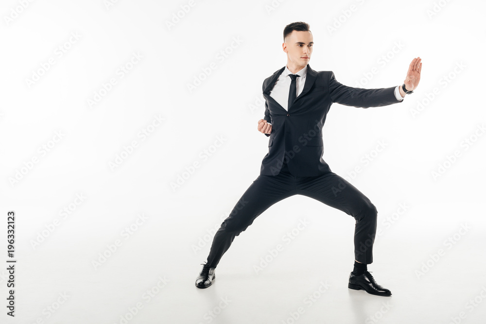 handsome businessman standing in karate position in suit isolated on white