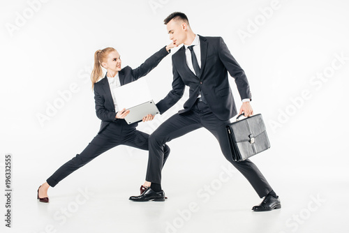 young businesspeople in suits fighting for laptop isolated on white