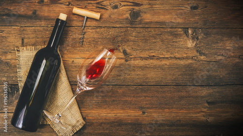 A bottle of wine and a wine glass on a wooden background. view from above.
