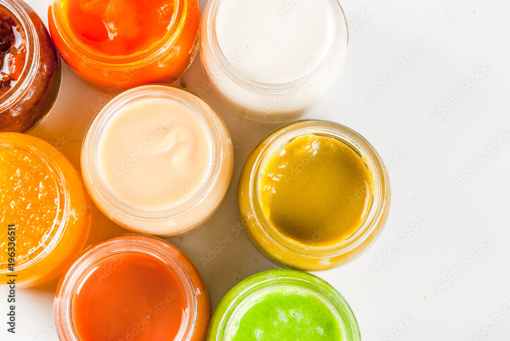 Variety of homemade baby vegetable and fruit puree, white marble background copy space top view Variety of homemade baby vegetable and fruit puree, white marble background copy space top view