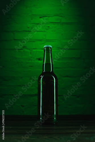 close-up view of single green beer bottle in green light