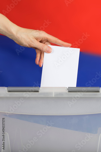 Female hand casts ballot paper in the ballot box.