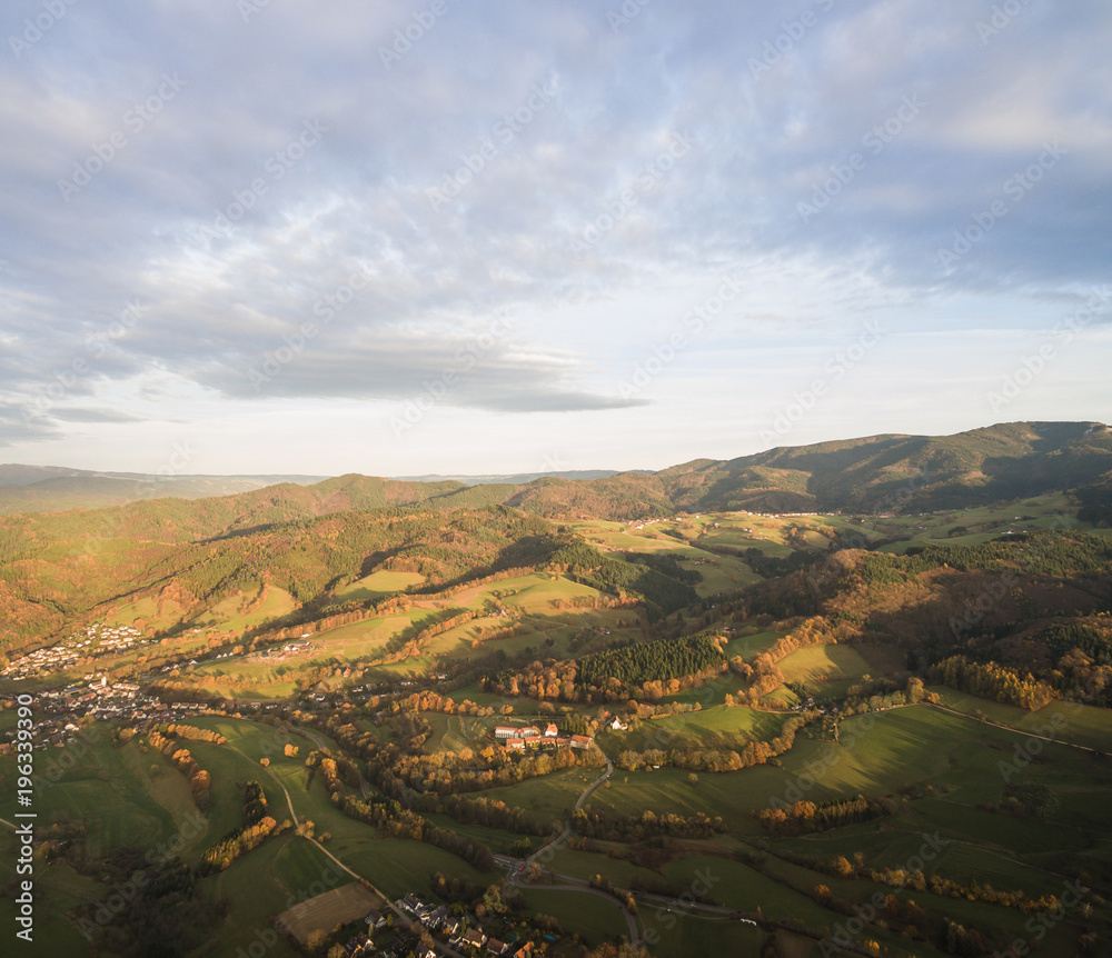 aerial view of beautiful green hills with trees and buildings at sunlight, Germany