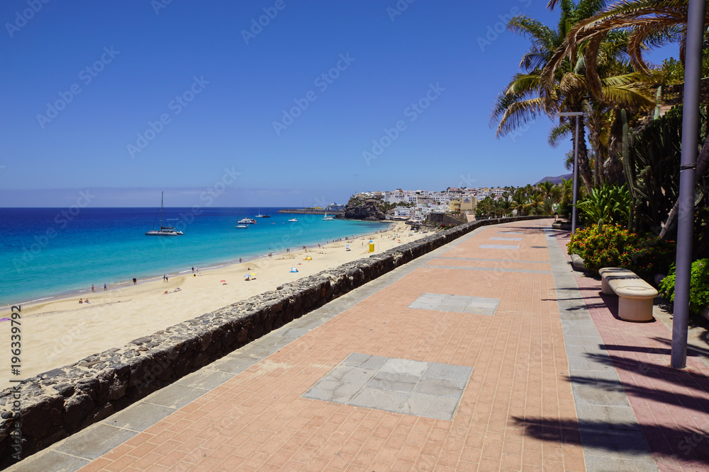 Promenade with tropical plants and flowers along a beach in Morro Jable holiday village, Fuerteventura, Canary Islands, Spain