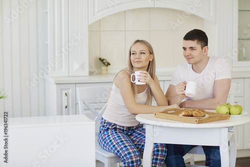 Loving happy couple in their pajamas in the morning eating breakfast in the kitchen. photo