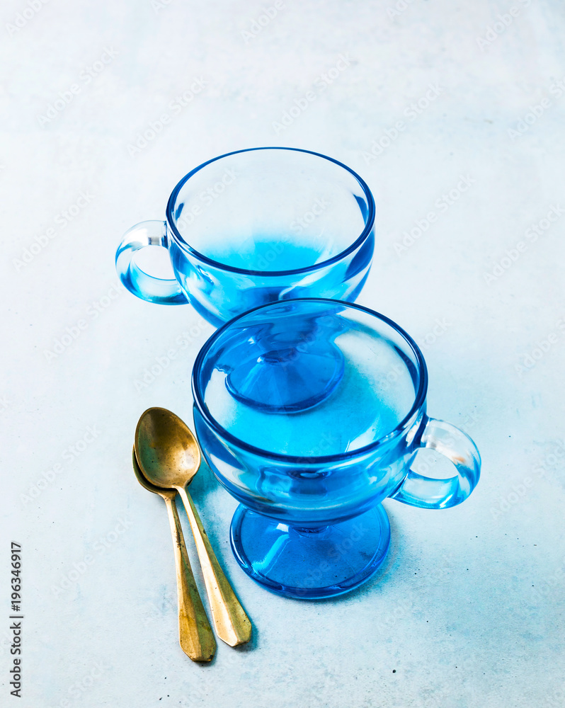 two empty glass blue ice cream cups and spoons on the table.