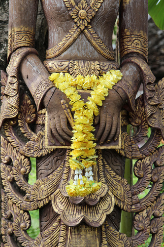 Hand of deva wood carving with yellow flower garland. photo