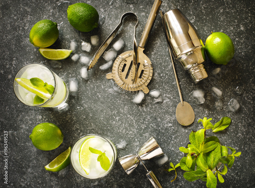 Mojito cocktail with lime and mint in glass on a stone table. Bar tools and ingredients for cocktail.